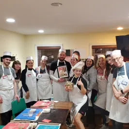 Group of people wearing aprons and hats posing together in a room.