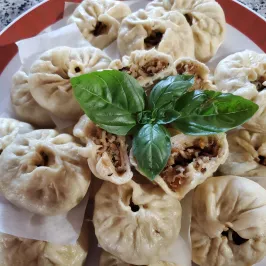 Steamed dumplings on a plate with basil garnish.